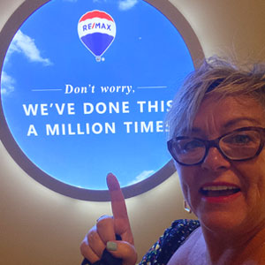 Anita Van Rootselaar in front on a REMAX illuminated sign: Don't worry, we've done this a million times!